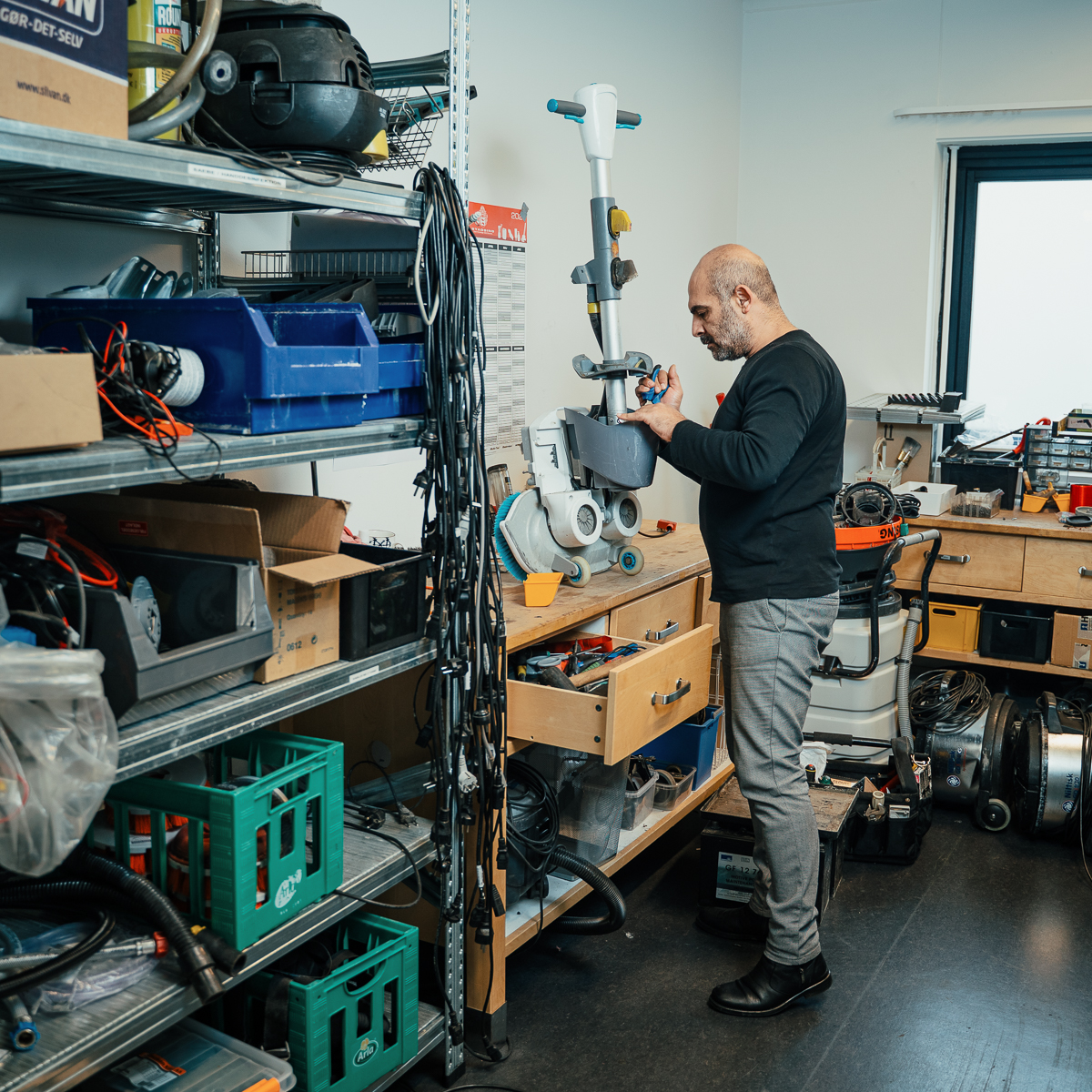 Technician servicing a cleaning scrubber machine in an equipment workshop in Denmark